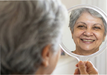imagem de uma senhora olhando o espelho e sorrindo